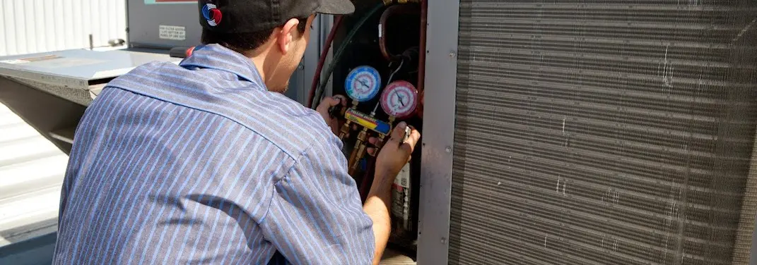 HVAC technician servicing a condenser unit in Monroeville