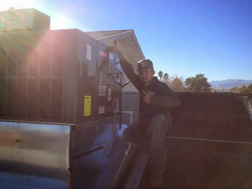 HVAC technician performing AC Tune-Up on a rooftop unit in Monroeville